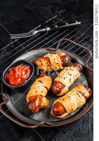 Pigs in Blanket puff pastry sausage wrap roll. Black background. Top view 120874611