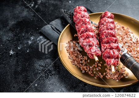 Raw kofta, kofte kebab Skewers with beef and lamb meat and spices. Black background. Top view. Copy space Raw kofta, kofte kebab Skewers with beef and lamb meat and spices. Black background. Top view. Copy space 120874622