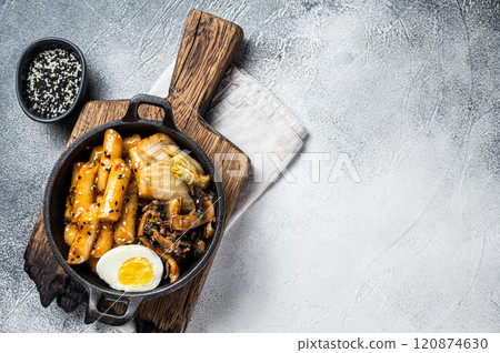 Tteokbokki, Topokki stick rice cake in spicy sauce with egg and mashrooms. White background. Top view. Copy space 120874630