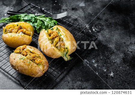 Turkish Kumpir, baked potatoes stuffed with cheese, bacon, salty cucumber, herbs and butter. Black background. Top view. Copy space 120874631
