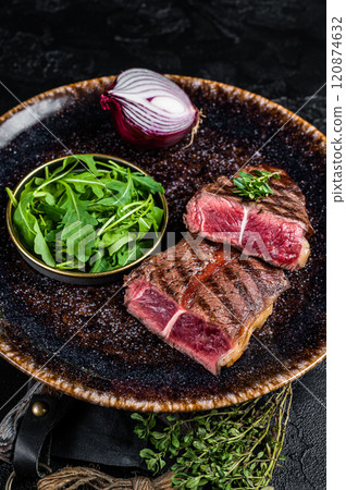 Grilled Oyster Top Blade beef meat steak on a plate with salad. Black background. Top View 120874632