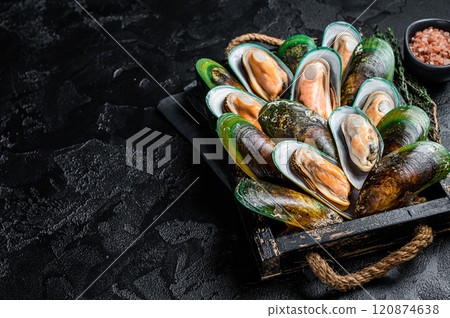 Boiled Green mussels with herbs in a wooden tray. Black background. Top view. Copy space 120874638