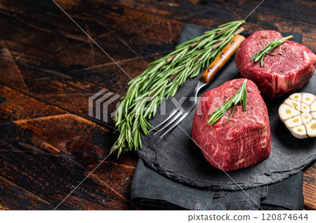 Raw Fillet Mignon Beef steak with herbs and garlic, marble meat. Wooden background. Top view. Space for text Raw Fillet Mignon Beef steak with herbs and garlic, marble meat. Wooden background. Top view. Space for text 120874644