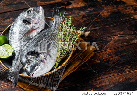 Fresh raw sea bream dorado fish with herbs. Black background. Top view. Copy space 120874654