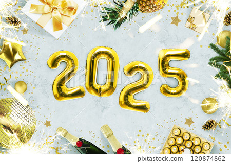 New Year 2025, creative idea. Golden balloons 2025 lie on a gray concrete table with fireplaces, candies, a golden disco ball, champagne and a Christmas tree, top view. Christmas card 2025 New Year 2025, creative idea. Golden balloons 2025 lie on a gray concrete table with fireplaces, candies, a golden disco ball, champagne and a Christmas tree, top view. Christmas card 2025 120874862