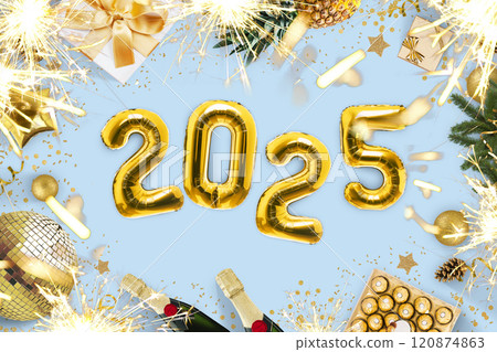 New Year 2025, creative idea. Golden balloons 2025 lie on a blue table with fireplaces, candies, a golden disco ball, champagne and a Christmas tree, sparks bengal top view. Christmas card 2025 New Year 2025, creative idea. Golden balloons 2025 lie on a blue table with fireplaces, candies, a golden disco ball, champagne and a Christmas tree, sparks bengal top view. Christmas card 2025 120874863