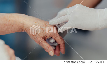 Close up of nurse administrating medication throught IV. Old woman with serious health issues. IV, intravenous therapy for elderly patient. 120875401