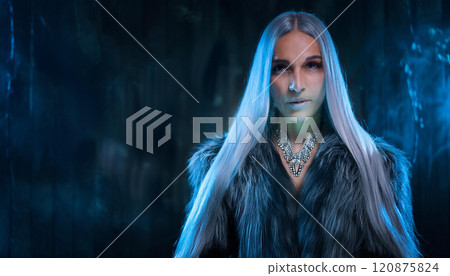 A woman with long hair and a necklace stands in front of a dark background 120875824