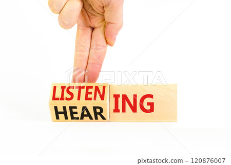 Listening or hearing symbol. Businessman turns wooden cubes and changes a concept word Listening to Hearing. Beautiful white background. Copy space. Business educational listening or hearing concept. 120876007