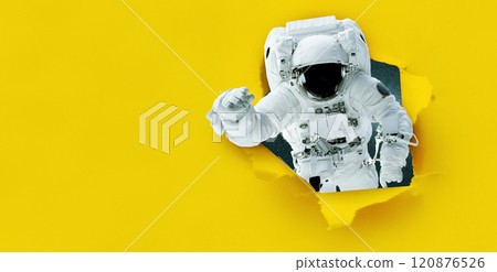Space man astronaut tears paper from hole, concept. Yellow banner for design and text. Creative idea. Travel to space Space man astronaut tears paper from hole, concept. Yellow banner for design and text. Creative idea. Travel to space 120876526