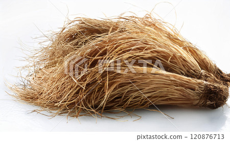 A bunch of dry, brown straw is laying on a white surface 120876713