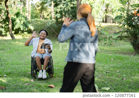 Disabled Young Man in Wheelchair Cheerfully Greets Friend in Park Setting, Embracing Friendship and Inclusivity Disabled Young Man in Wheelchair Cheerfully Greets Friend in Park Setting, Embracing Friendship and Inclusivity 120877161