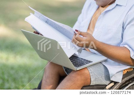 Young Disabled Businessman in Wheelchair Conducting Outdoor Work Inspection with Laptop and Documents in Hand 120877174