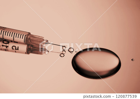Injection syringe with a drop of drug on a stainless steel background. Injection syringe with a drop of drug on a stainless steel background. 120877539