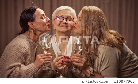 Happy Mothers day. Two elderly women, daughter's greeting their old mother with her day, drinking wine, laughing, showing respect and love 120877963