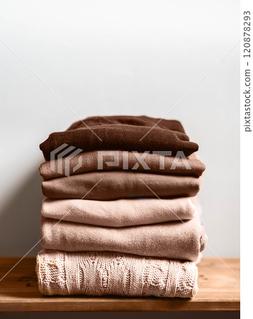 Pile of brown autumn clothes on wooden background, sweaters, knitwear, copy space 120878293