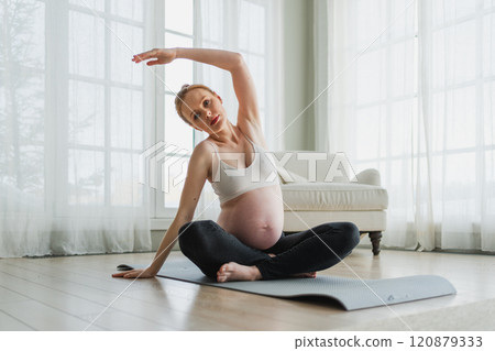 Pregnancy yoga fitness workout training. Pregnant woman practicing yoga at home. Pregnant girl doing sports exercise on yoga mat indoor. Woman with big belly have fitness training practicing asana 120879333