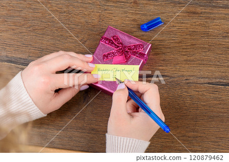 Handwritten note Happy Christmas on gift box, pen in female hands. 120879462