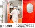 Butcher opening red door in food processing plant 120879533