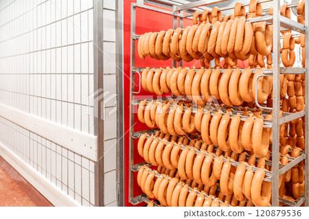 Sausage production line showing smoked sausages hanging in a modern food processing facility 120879536