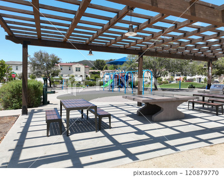 Covered gathering area in city park with green wood picnic tables 120879770