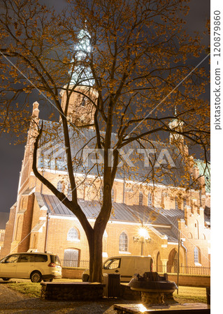 A captivating night photograph of a historic brick church tower illuminated against a dark sky. The image captures the architectural details and the spiritual atmosphere of the scene.  120879860