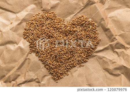 Golden wheat grains in the shape of a heart lie on a background of craft paper 120879976