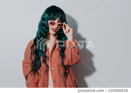 Cheeky fashion hipster girl with colored long hair, mocha color lips and jacket looking through sunglasses on white background. Stylish, Playful woman. Trendy fashion outfit. Color of the 2025 year. 120880026