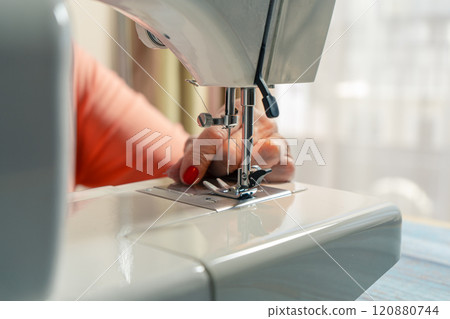 Hands of an elderly woman threading the needle of the sewing machine before starting. Hands of an elderly woman threading the needle of the sewing machine before starting. 120880744