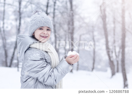 Smiling girl holding a snowball in the winter forest Smiling girl holding a snowball in the winter forest 120880788
