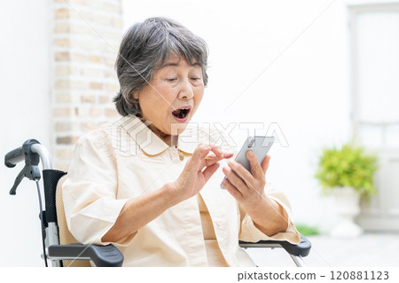 坐在輪椅上操作智慧型手機的高級女性 120881123