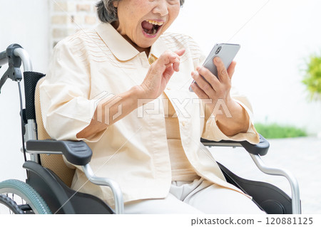 Senior woman in a wheelchair operating a smartphone Senior woman in a wheelchair operating a smartphone 120881125