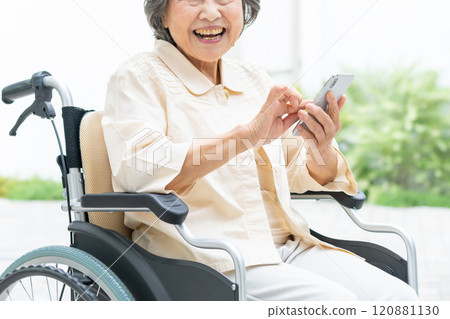 Senior woman in a wheelchair operating a smartphone 120881130