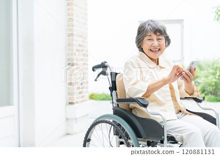 Senior woman in a wheelchair operating a smartphone Senior woman in a wheelchair operating a smartphone 120881131