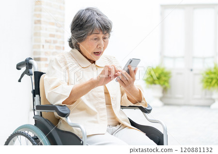Senior woman in a wheelchair operating a smartphone Senior woman in a wheelchair operating a smartphone 120881132