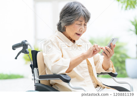 Senior woman in a wheelchair operating a smartphone Senior woman in a wheelchair operating a smartphone 120881139