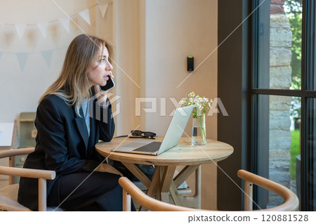 Focused businesswoman talking on phone, working on laptop in cafe. Remote job, business meeting wait 120881528