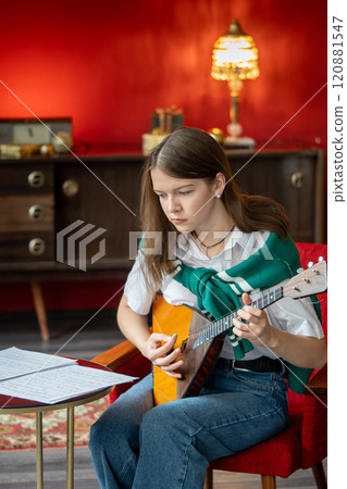 Concentrated woman rehearsing balalaika song, reading note sheet, practice for concert or class 120881547