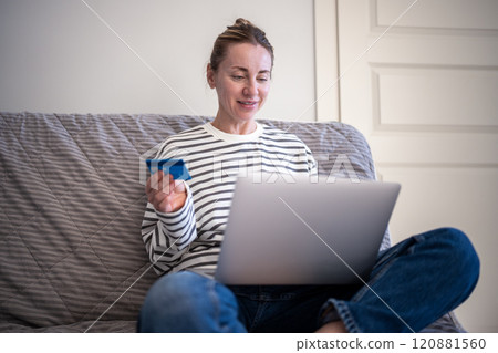 Happy woman resting on couch with laptop and credit card. Internet online shopping, home delivery. 120881560