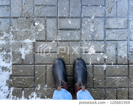 Winter boots on road with rock salt, top view. Chemical reagents to melt ice, prevent icing Winter boots on road with rock salt, top view. Chemical reagents to melt ice, prevent icing 120881569