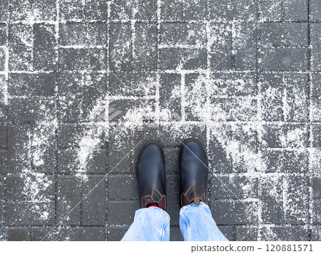 Winter boots on road with rock salt, top view. Chemical reagents to melt ice, prevent icing 120881571
