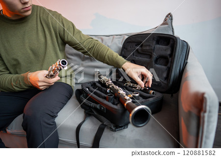 Man hands puts disassembled black clarinet in special case, inspects parts of flute after playing it Man hands puts disassembled black clarinet in special case, inspects parts of flute after playing it 120881582