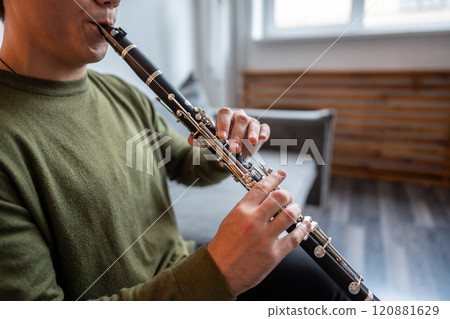 Clarinet player. Clarinetist hands playing flute woodwind music instrument at home. Guy plays oboe Clarinet player. Clarinetist hands playing flute woodwind music instrument at home. Guy plays oboe 120881629
