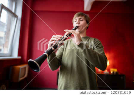 Clarinet player. Clarinetist hands playing flute woodwind music instrument at home. Guy plays oboe 120881639