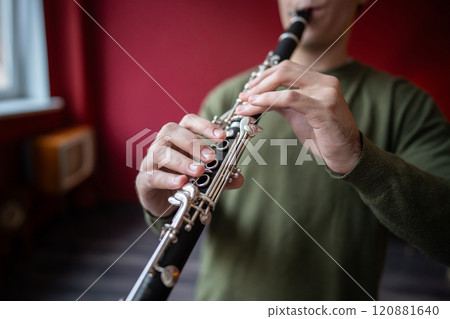 Clarinet player. Clarinetist hands playing flute woodwind music instrument at home. Guy plays oboe 120881640