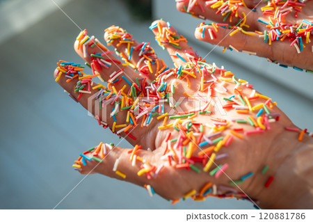 Hand covered in colorful baking sprinkles for donuts, cakes, sweet desserts and Easter cupcake. Hand covered in colorful baking sprinkles for donuts, cakes, sweet desserts and Easter cupcake. 120881786