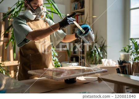 Concentrated woman, liquid artist creating pattern on canvas while working with epoxy resin painting 120881840