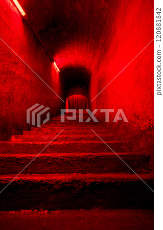 Dark eerie staircase leading to underground space illuminated by red neon light, mysterious tunnel 120881842