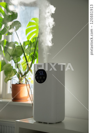 Modern humidifier at home, moistens dry air surrounded by indoor plant. Apartment with moisturizer.  120881913