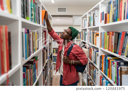 Nerd student african american man choosing book in university library taking it from shelf. 120881975